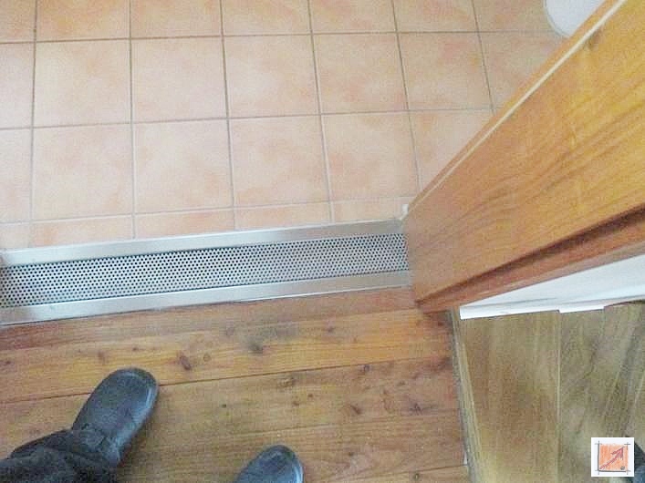 Detailaufnahme einer hochwertig verarbeiteten Edelstahlrinne mit dekorativem Lochmuster im Übergang zum Holzboden.